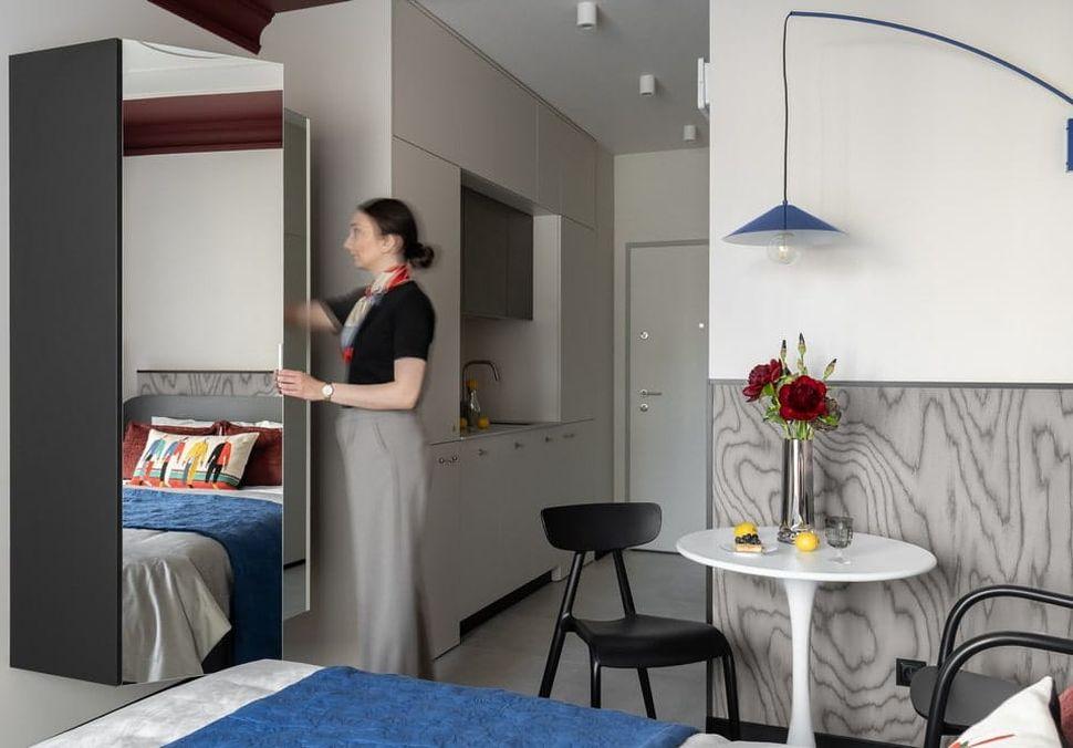 Zrcadlová dvířka šatní skříně odrážejí pokoj a opticky ho zvětšují. Vedle skříně je vidět vstup do kuchyňské niky. (Foto: Inkadr / Natalia Kaczmarek)