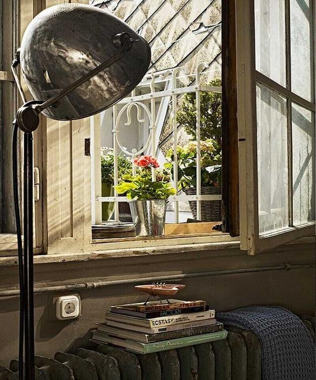 Patinu okenních rámů a litinového radiátoru doplňuje kovová lampa. Knihy a květiny dodávají pracovnímu zákoutí útulnost. (Foto: A+Z Design Studio)